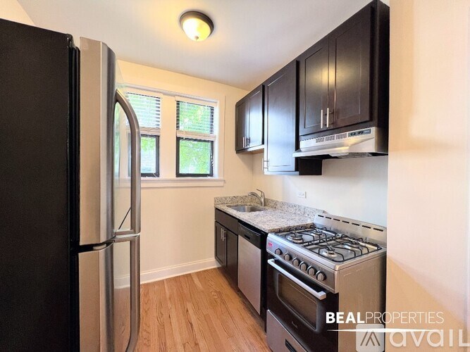 A kitchen with black cabinets and a stainless steel refrigerator.