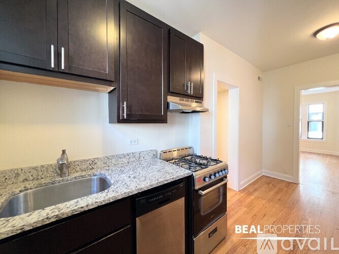 A kitchen with a stove, sink, and cabinets.
