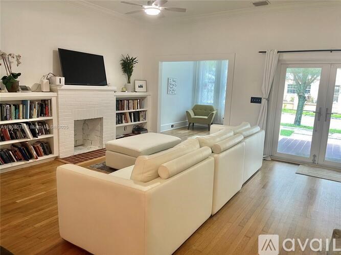 A living room with a white couch, a fireplace, and a television.