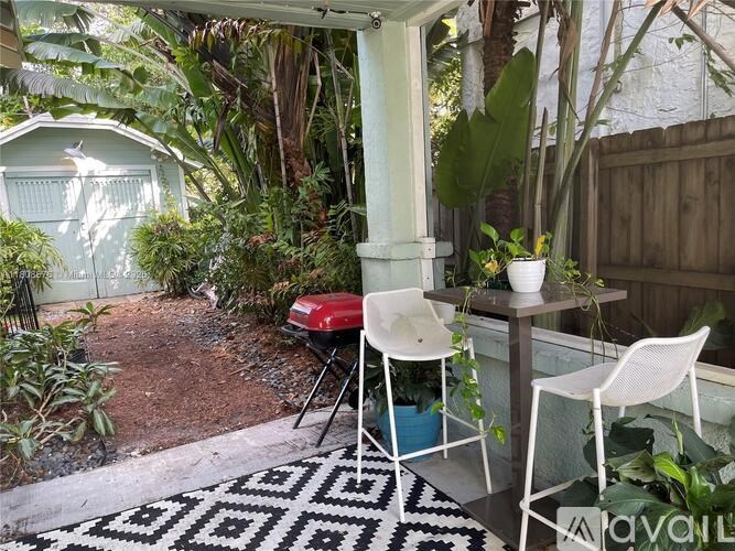 A patio with a table and chairs surrounded by plants.