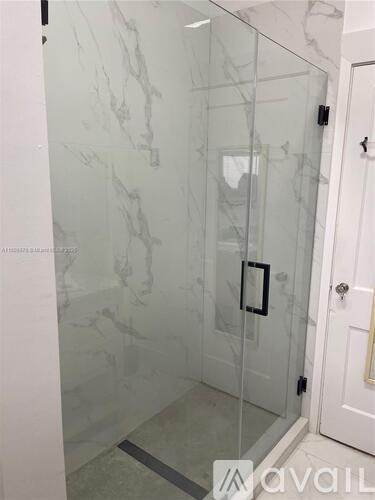 A glass shower door with a black handle.
