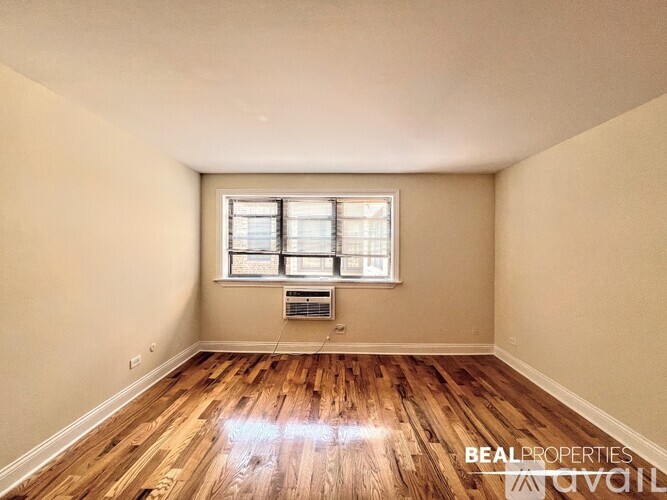 A room with wooden floors and a window with blinds.