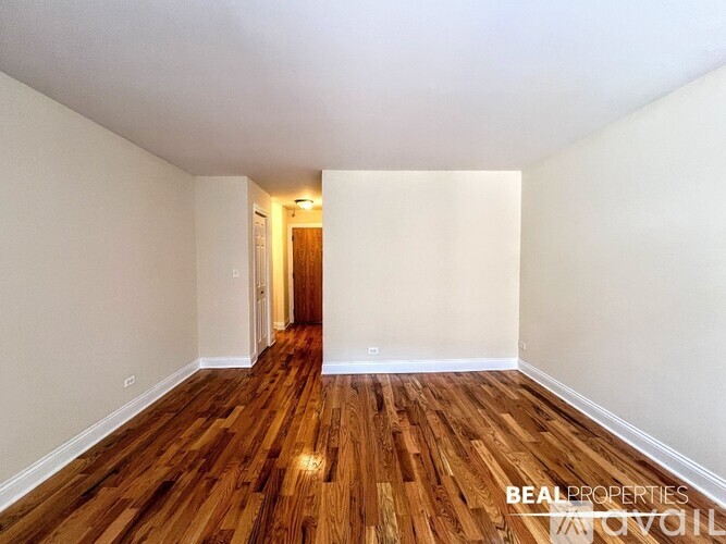 A room with wooden floors and white walls, with a doorway leading to another room.