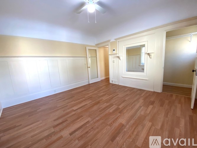 A room with wooden flooring and white walls.