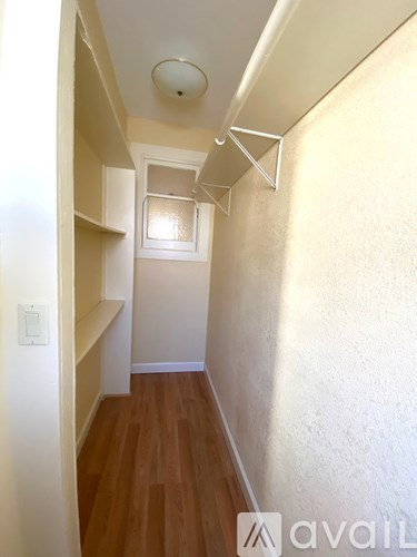 A narrow hallway with wooden floors and white walls.