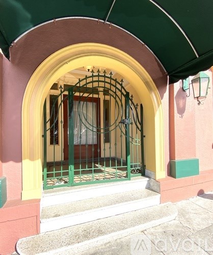A green gate is in front of a yellow door.