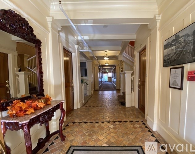 A long hallway with a table and chairs on the left and a framed picture on the wall on the right.