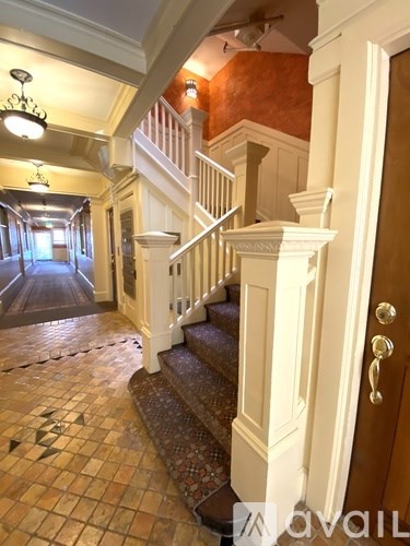 A hallway with a staircase and a chandelier.