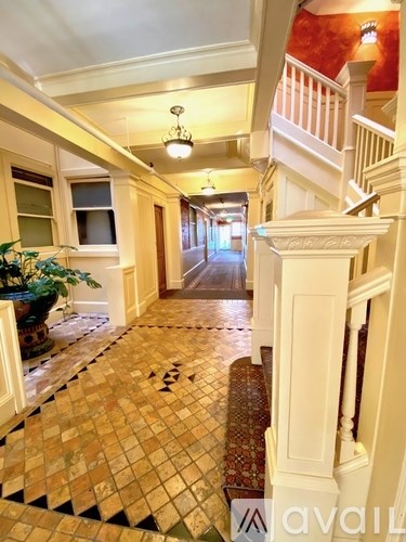 A hallway with a tiled floor and a staircase on the right side.