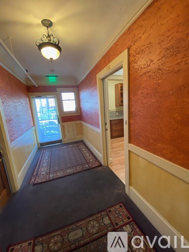 A hallway with a red carpet and a chandelier.