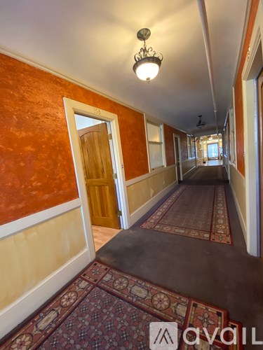 A hallway with a rug on the floor and a chandelier hanging from the ceiling.