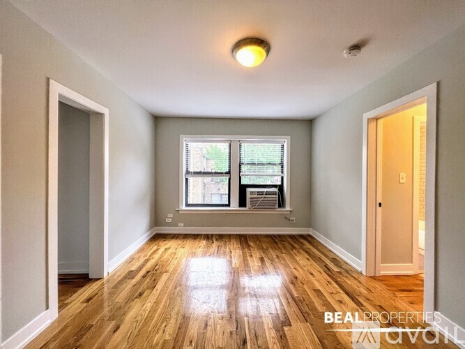 A spacious room with wooden floors and a large window.