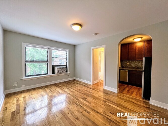 A room with wooden flooring and a window with blinds.