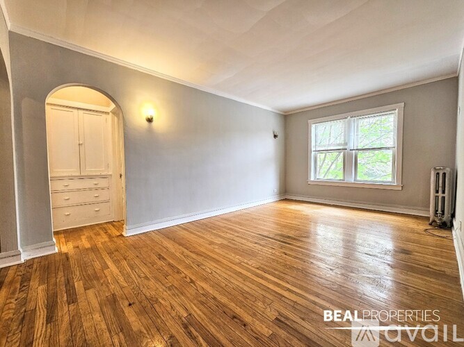 A room with wooden flooring and a window letting in natural light.