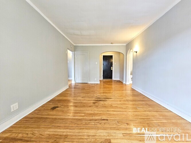 A long hallway with wood floors and white walls.