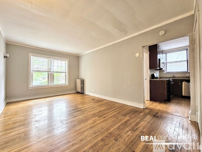 A spacious room with wooden flooring and a window.