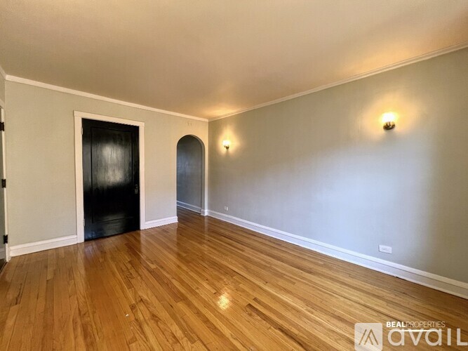 A room with wooden floors and a black door.
