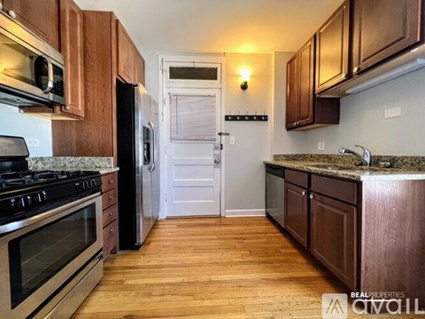 A kitchen with wooden cabinets and a white door in the background.