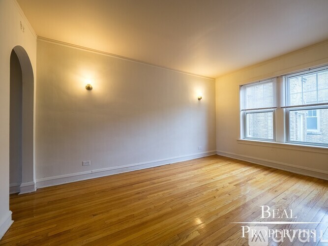 A room with wooden floors and white walls, with a window on the right side.