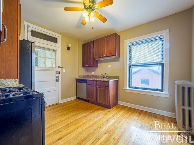 A kitchen with a black fridge and wooden floors.