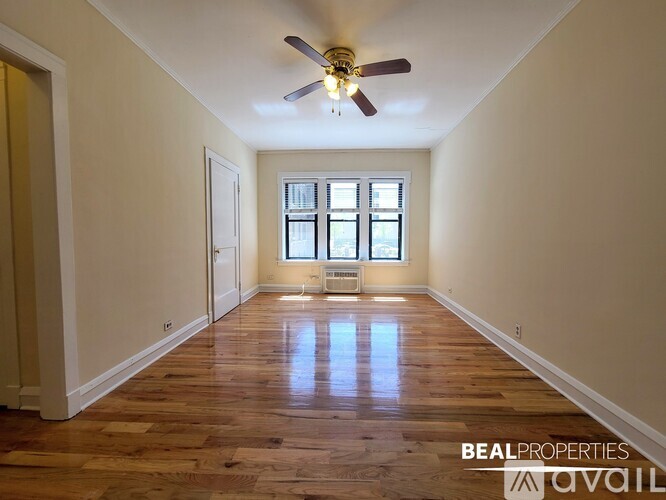 A spacious room with wooden floors and a ceiling fan.