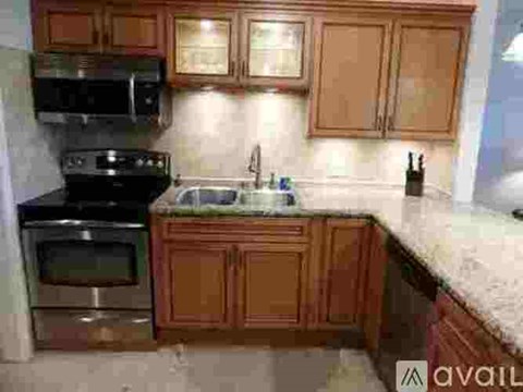 A kitchen with brown cabinets and a black stove top oven.