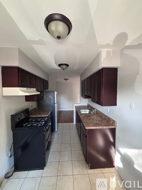 A kitchen with a black stove top oven and brown cabinets.