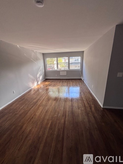 A room with wooden flooring and a window.