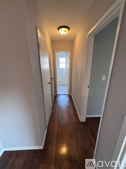 A long hallway with wood floors and white walls.