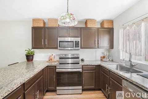 A kitchen with brown cabinets and granite countertops.