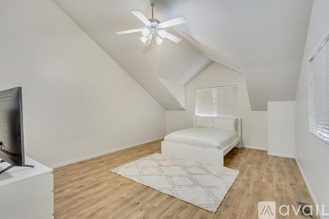 A bedroom with a bed and a ceiling fan.