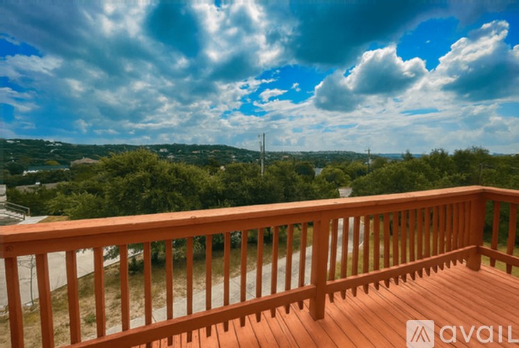 A wooden deck overlooks a landscape with a cloudy sky overhead.