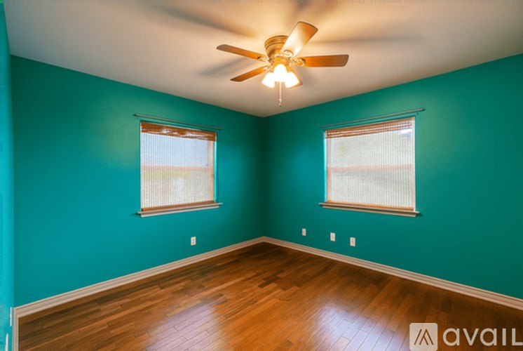 A room with a ceiling fan and two windows.