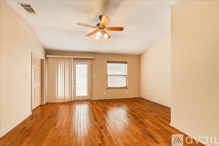 A spacious room with a ceiling fan and wooden flooring.