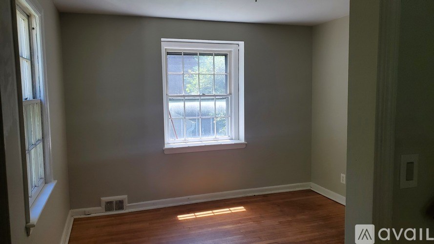 A room with a window and wooden flooring is available for rent.
