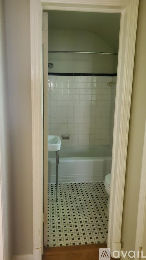 A bathroom with a glass shower door and a tiled floor.