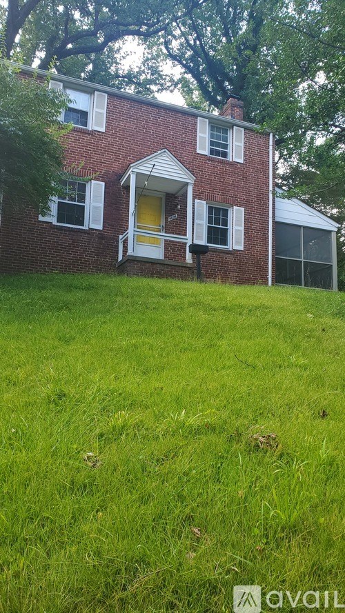 A red brick house with a white porch and a yellow door.