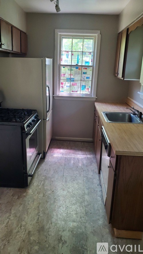 A kitchen with a black fridge and a window with a view of a garden.