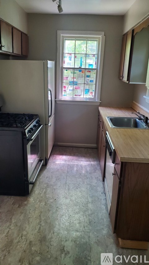 A kitchen with a black fridge and a window with a view of a garden.