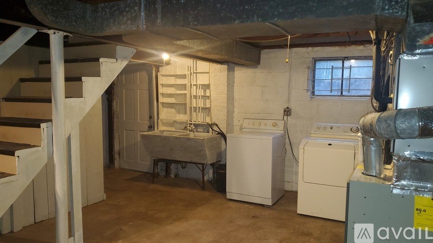A room with a staircase on the left and a washing machine and dryer on the right.
