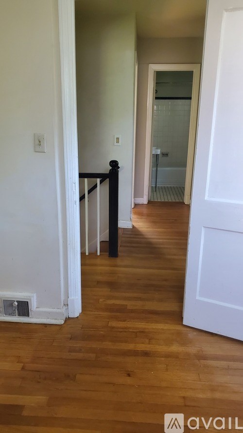A hallway with a wooden floor and white walls.