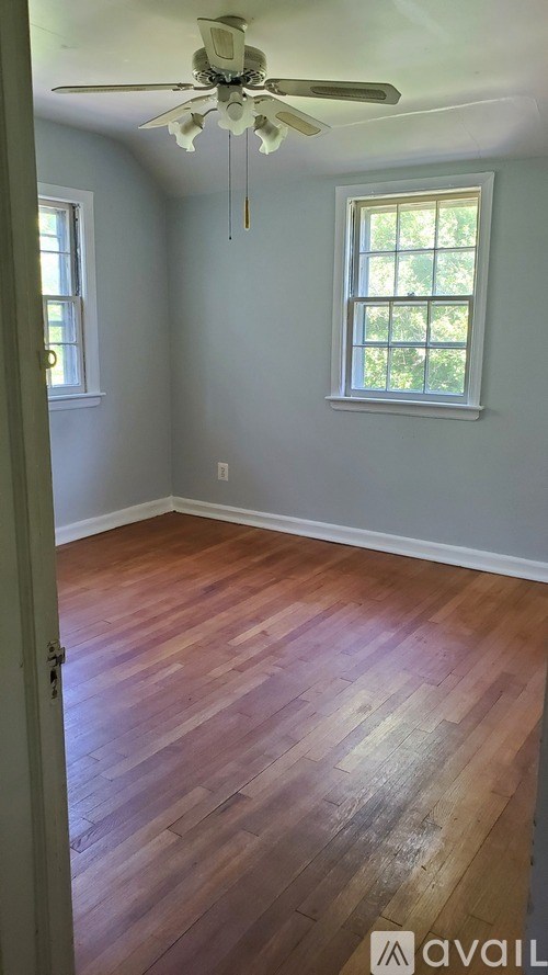 A room with a ceiling fan and wooden floors.