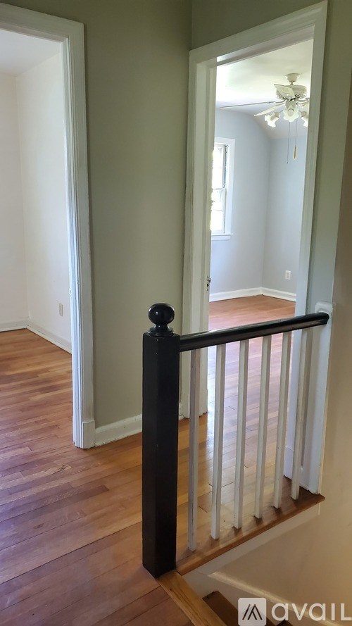 A hallway with a black railing and wooden floors.