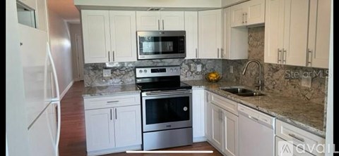 A kitchen with white cabinets and a granite countertop.