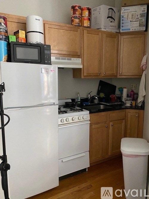 A kitchen with a white refrigerator, white stove, and wooden cabinets.