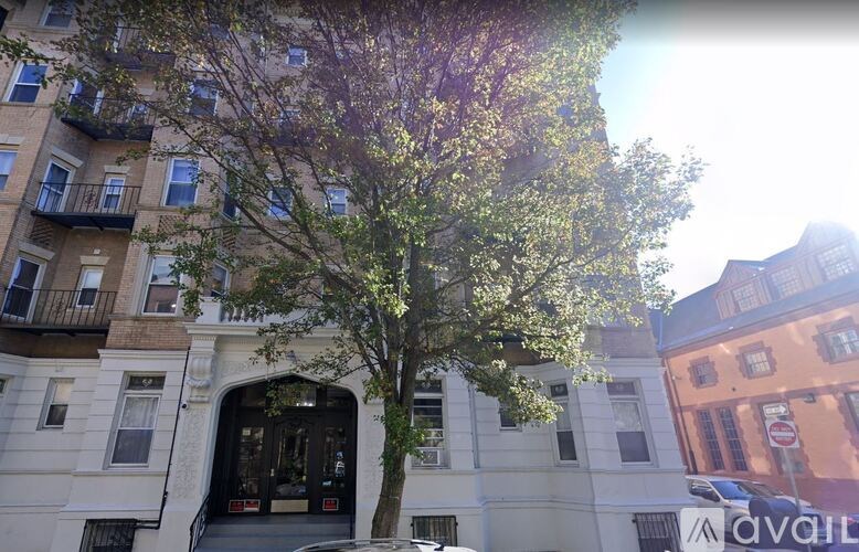 A tree in front of a building with a balcony.