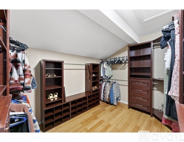 A walk-in closet with wooden shelves and drawers.