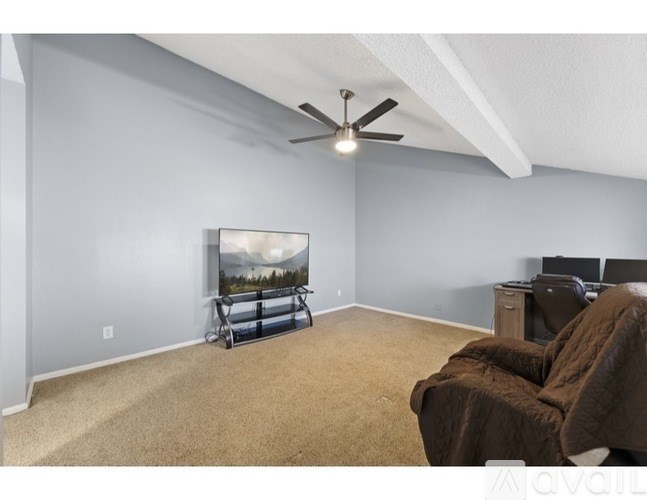 A living room with a television and a brown couch.