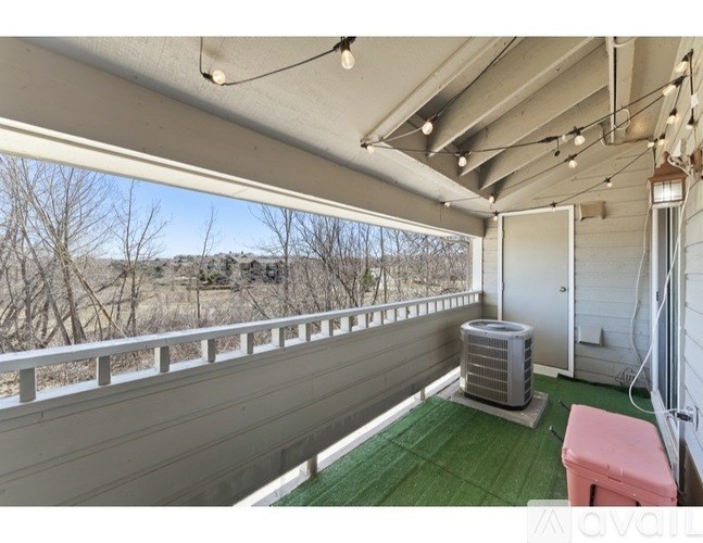 A balcony with a pink bench and a green mat.
