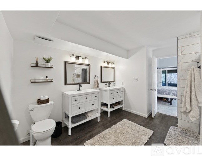 A white bathroom with a toilet, sink, and mirror.